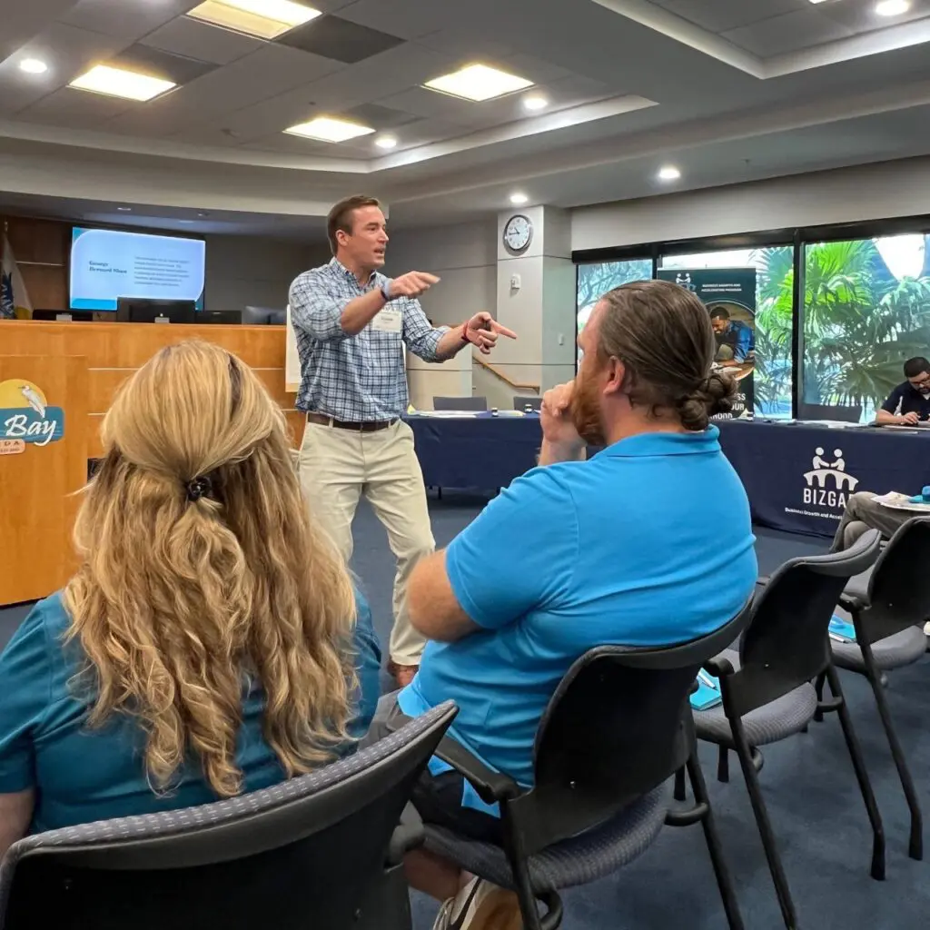 Presenter gesturing while teaching seated attendees at an entrepreneurship workshop.