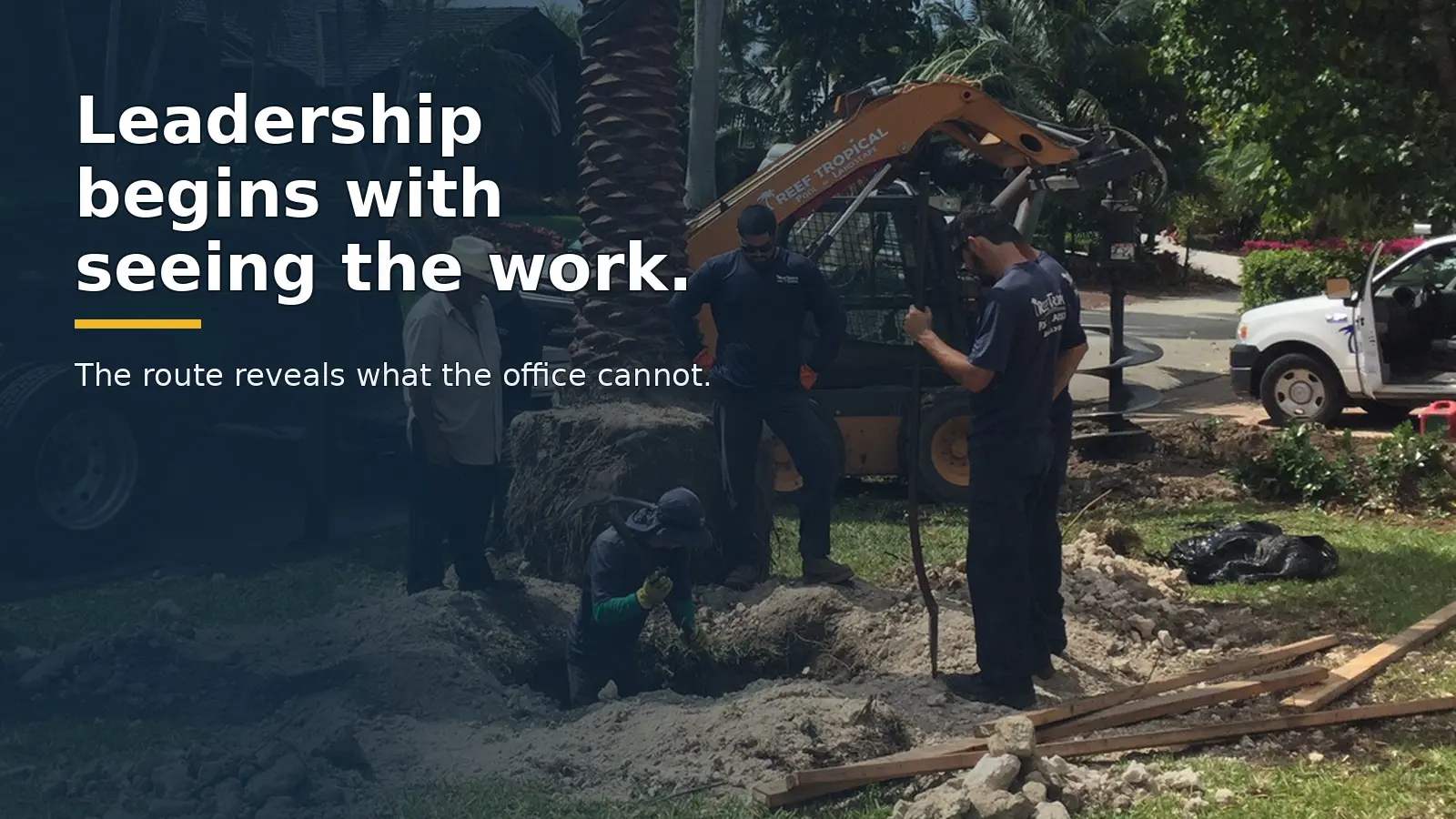 A field crew coordinates a palm installation with trucks and equipment at a South Florida jobsite.
