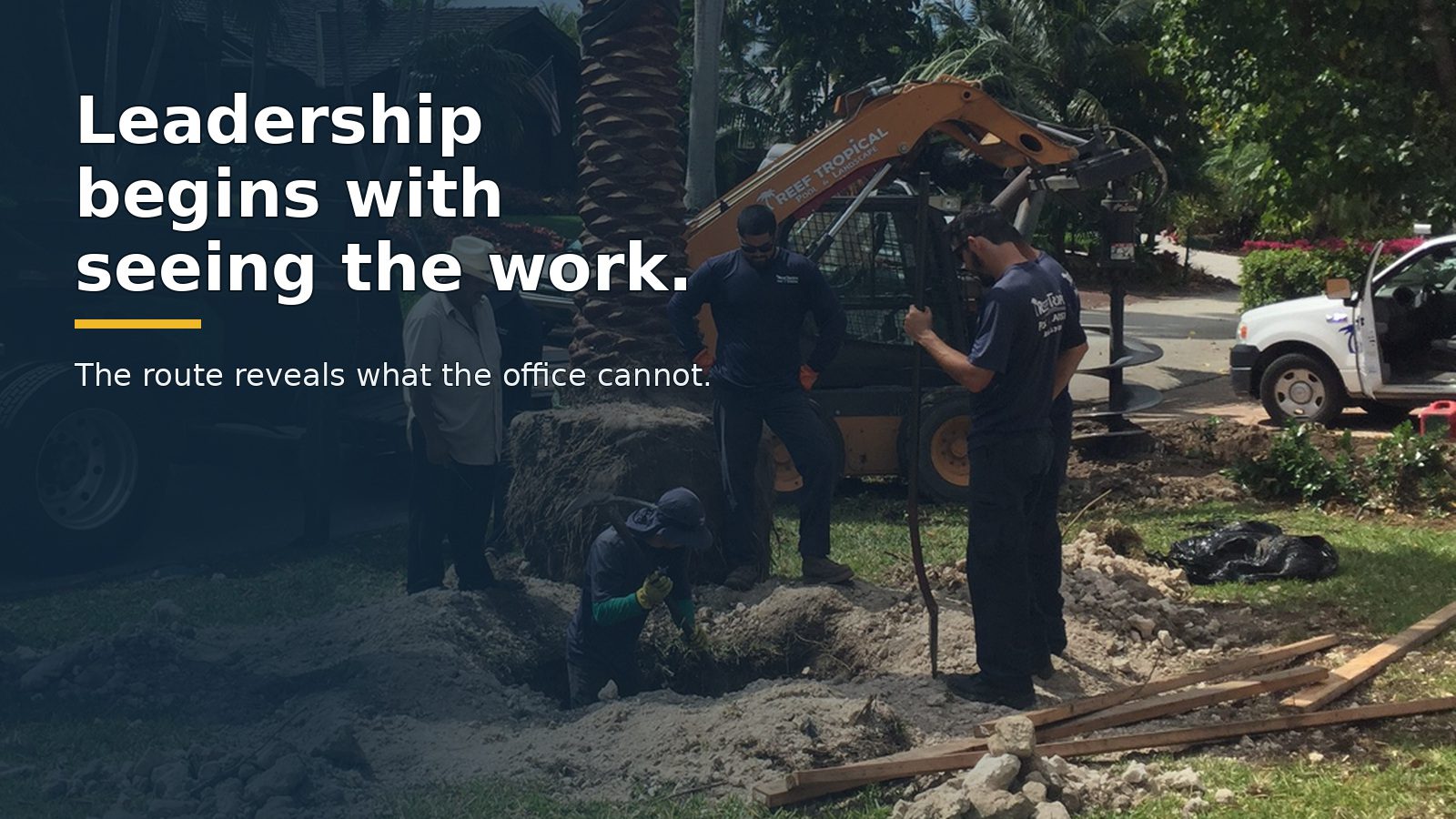 A field crew coordinates a palm installation with trucks and equipment at a South Florida jobsite.