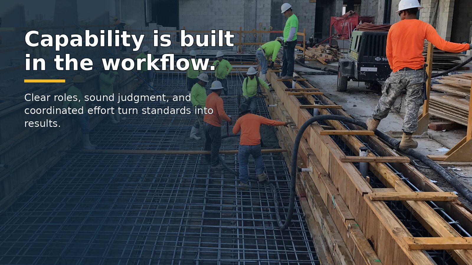 A coordinated field crew works around construction formwork and reinforcing steel.