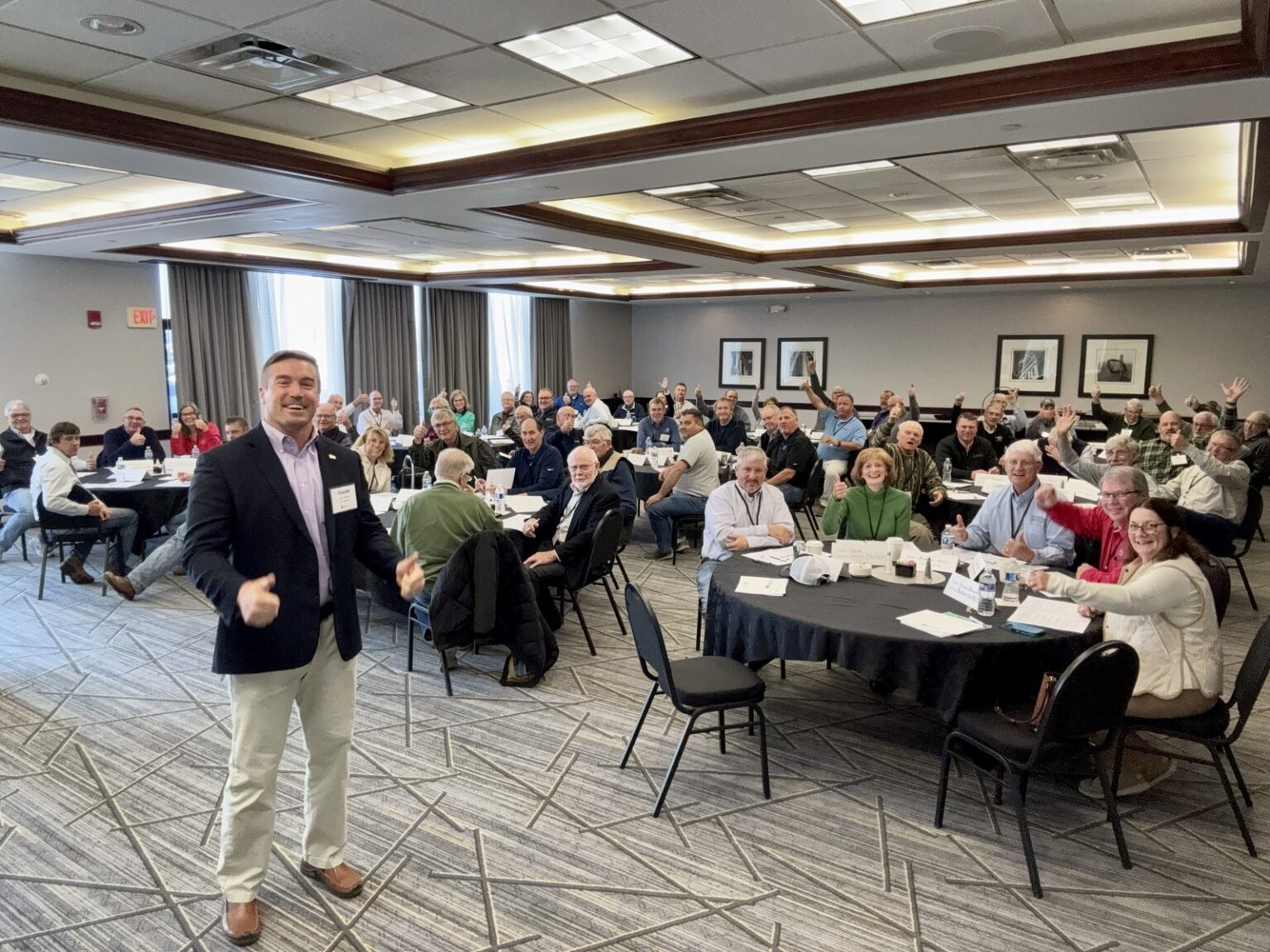 Dr. Claude Kershner leading a leadership workshop as a full room of business owners gives a thumbs up